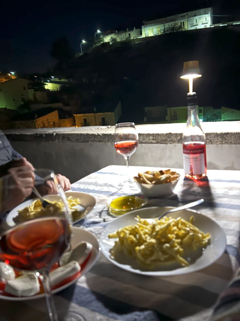 A cozy outdoor dinner in Abruzzo with pasta, olive oil, and wine under the night sky