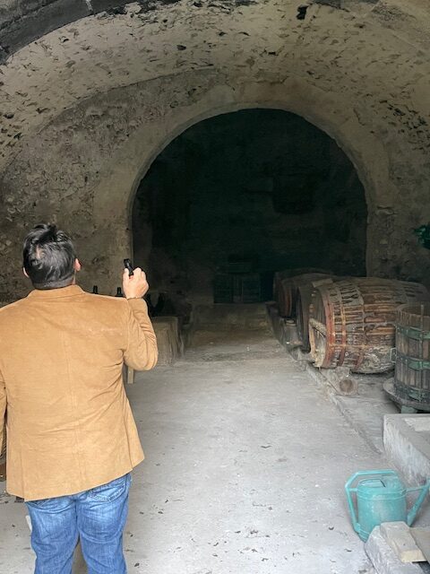 inspecting an old wine cellar with large wooden barrels inside a historic Italian property