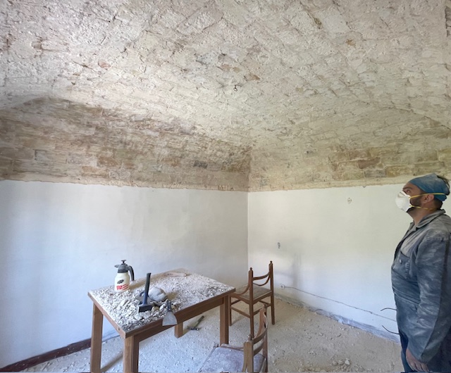 inspecting a newly uncovered brick ceiling in a historic Italian home, with tools and debris on a table from the renovation process