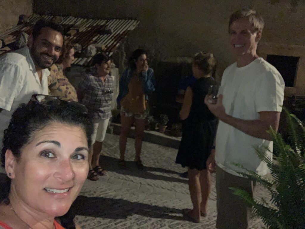 Group of friends in Italy smiling and enjoying an evening gathering outdoors, lit by ambient lighting