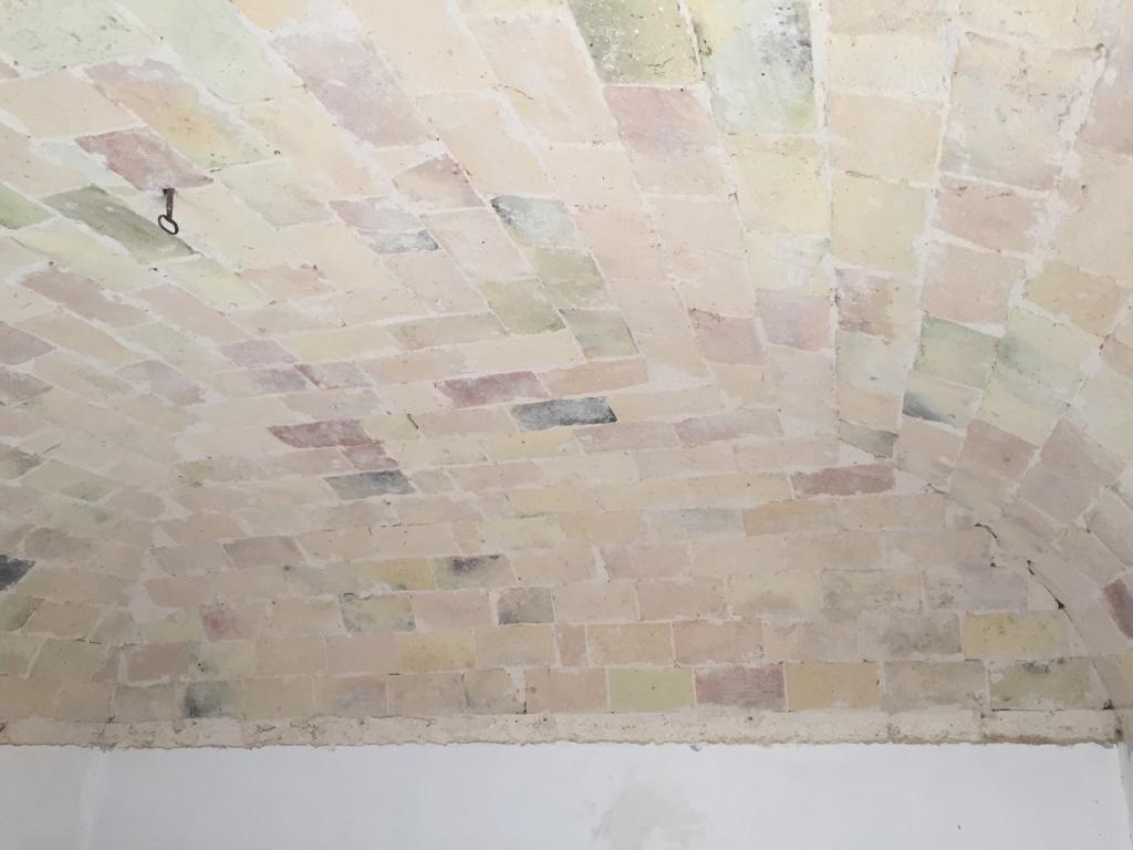 a newly uncovered brick ceiling in a historic Italian home, with tools and debris on a table from the renovation process