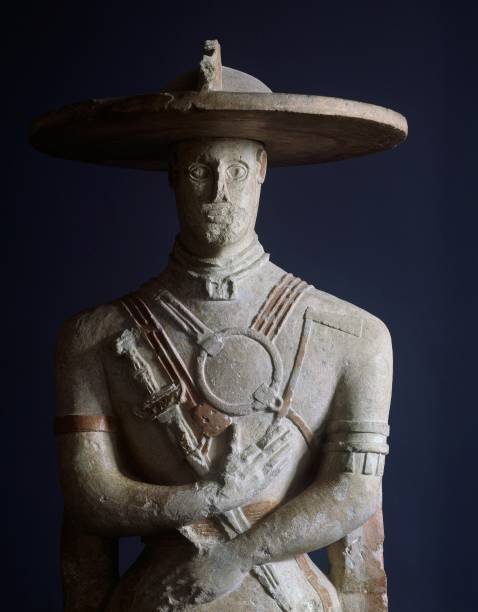 Ancient stone statue of a warrior with a wide-brimmed hat, featuring intricate armor details, from an Italian archaeological site