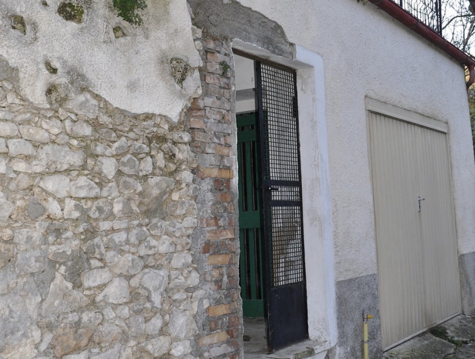 Rustic Italian wall with a traditional gate and garage door, blending modern design with historical elements