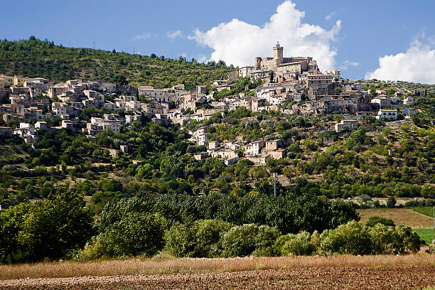 A picturesque hilltop village in the Italian countryside with historic stone buildings surrounded by vineyards 