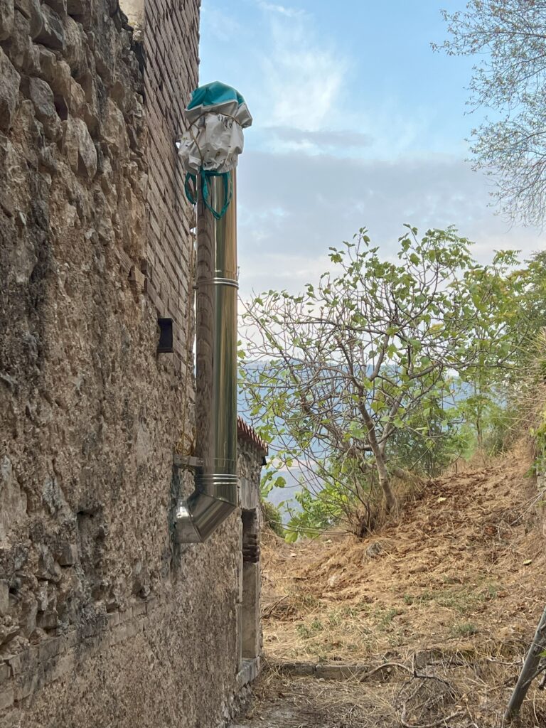 Partially installed wood oven stack on the exterior stone wall of an Italian home.