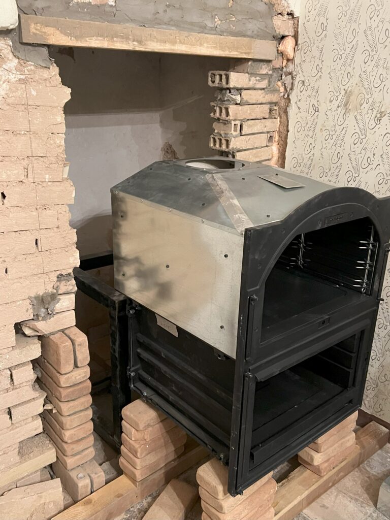 Partially installed wood oven inside a brick enclosure during an Italian kitchen renovation.