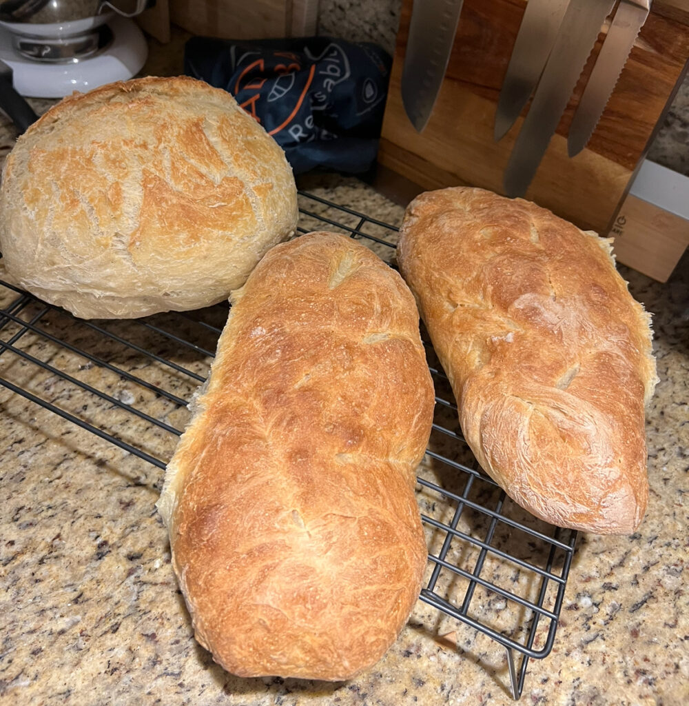 Freshly baked Italian bread loaves cooling on a wire rack in a rustic kitchen setting