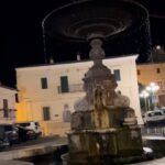 A charming stone fountain at the center of an Italian piazza, surrounded by historic buildings and lively cafes.