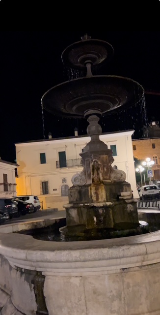 A charming stone fountain at the center of an Italian piazza, surrounded by historic buildings and lively cafes.