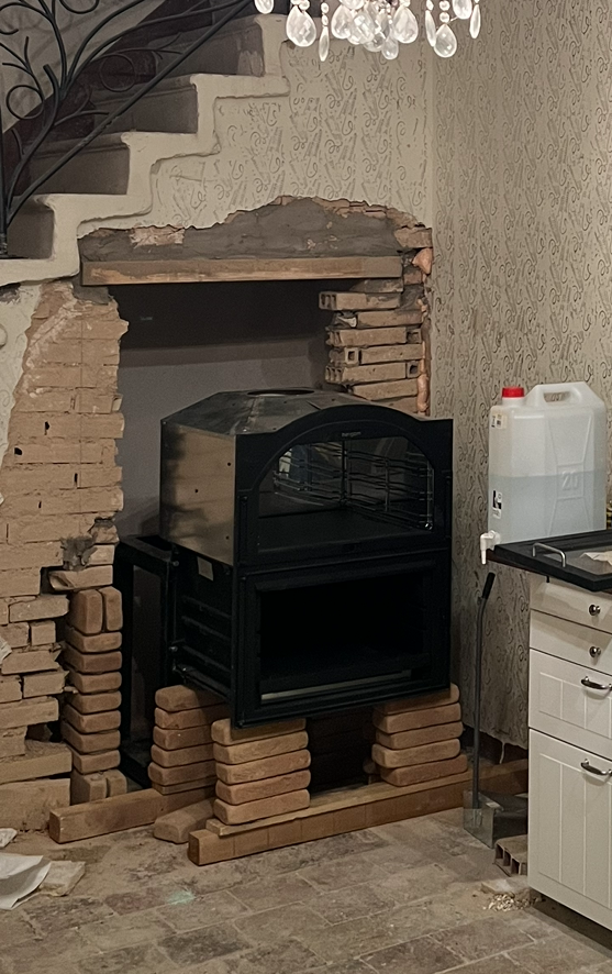 Assembling a wood oven within a brick enclosure during an Italian kitchen renovation.