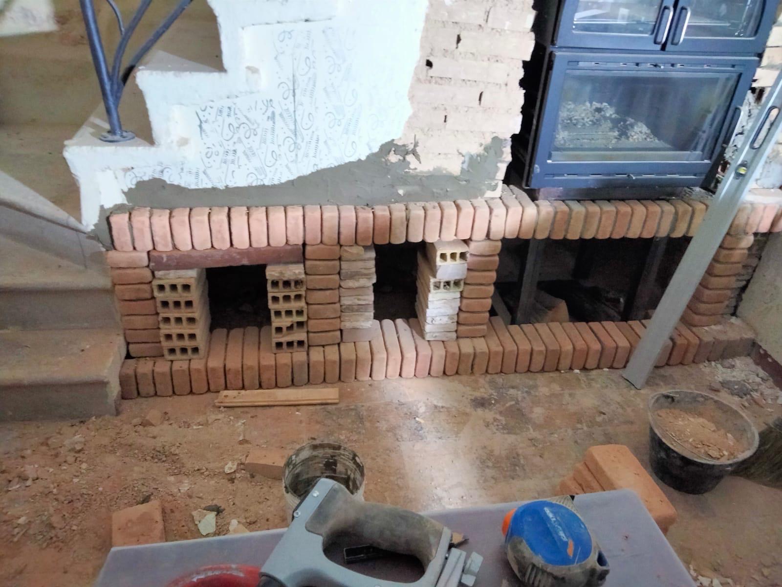 Brickwork and firewood opening being built beneath the wood-burning bread oven.