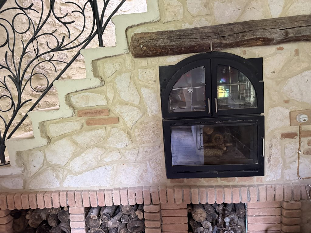 Finished wood-burning bread oven with limestone surround and brick firewood storage in our restored Italian kitchen.