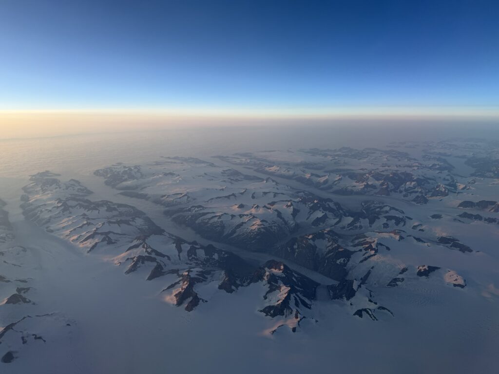 Aerial view of Greenland’s snow-covered mountains and frozen landscape from our flight to Iceland