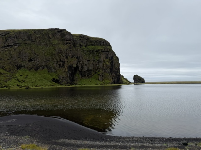 Dark cliffs and still water along Iceland’s South Coast during our counterclockwise Ring Road campervan trip.
