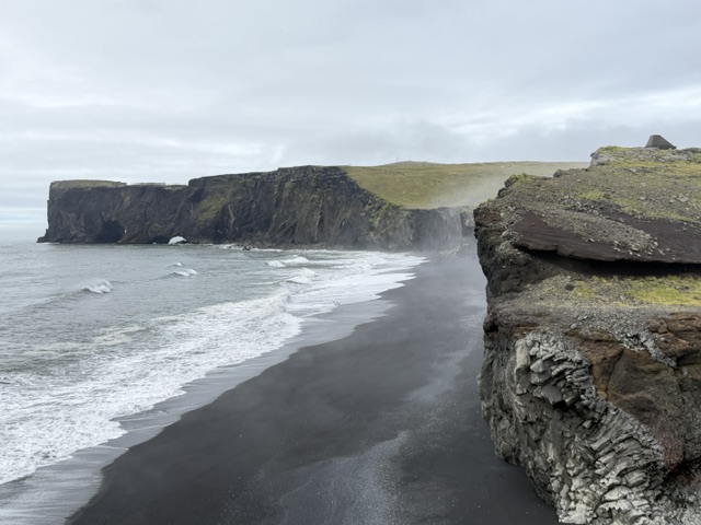 Black sand beach, ocean waves and rugged cliffs along Iceland’s South Coast.