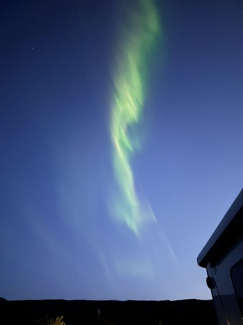 Green Northern Lights glowing above the Icelandic landscape at night.