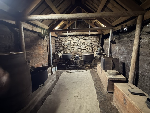 Interior of a reconstructed Viking longhouse with timber beams, stone walls and cooking area near Vestrahorn.