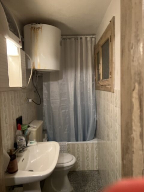 Water heater mounted directly above the toilet in our old Italian bathroom before renovation